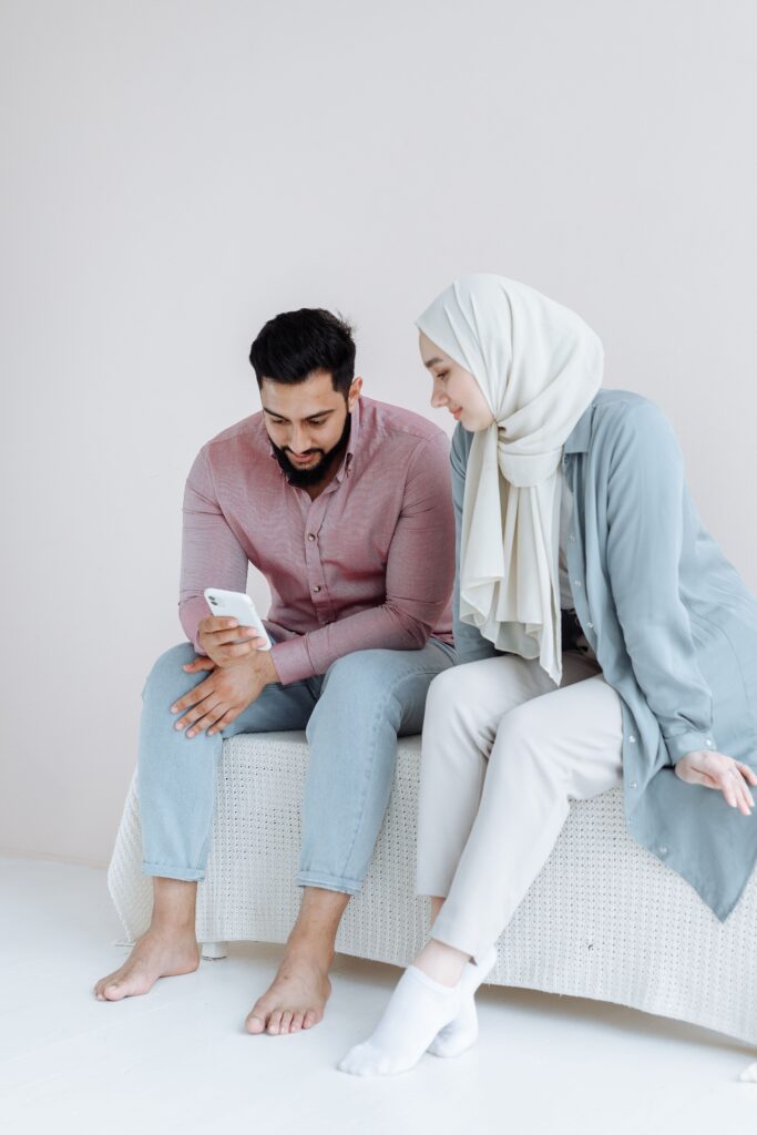 Muslim couple smiling together while looking at a phone
